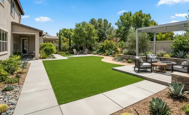Professionally designed backyard featuring artificial turf, paver patio, seating area, decorative landscaping, and integrated hardscape