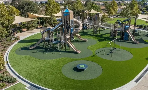 Engineered playground turf fall zone with shock absorption system beneath commercial play equipment