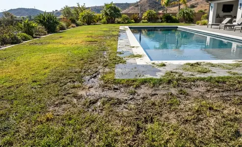 Luxury poolside artificial turf shown clean and pristine while nearby natural grass areas display muddy patches, grass clippings, puddling, and worn foot-traffic paths