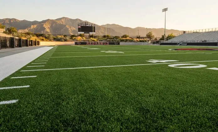 Close-up of premium quality artificial sports turf with dense emerald-green fibers, crisp white football yard line, and flawless professional installation