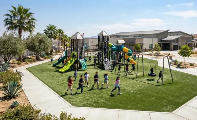 Large school playground with engineered artificial turf system and students playing safely in Inland Empire campus