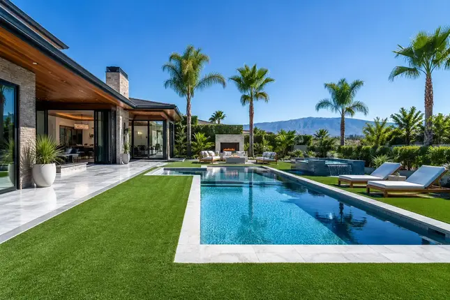 Luxury backyard pool area with slip-resistant synthetic turf surrounding modern pool deck